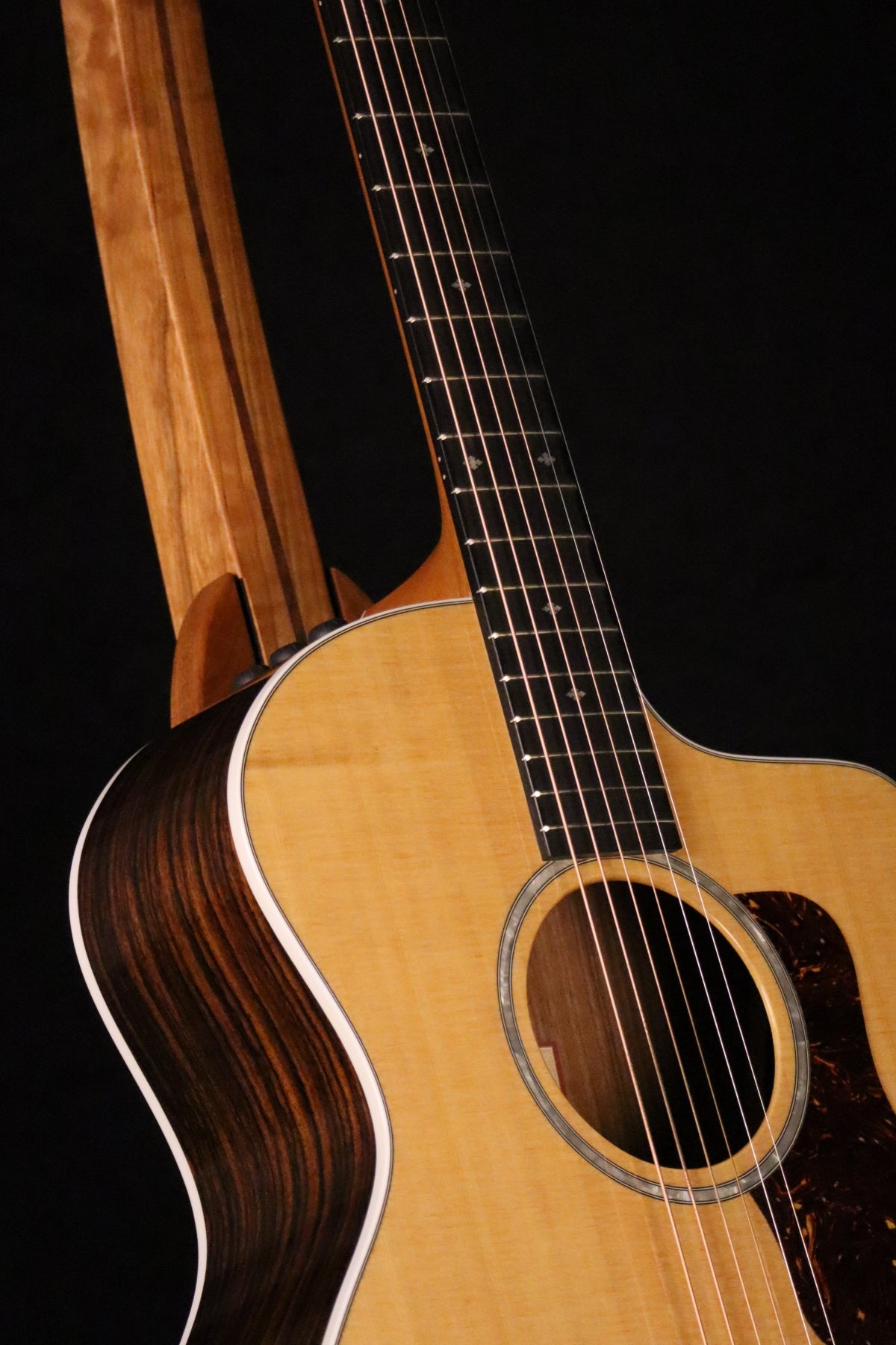 Folding cherry and walnut wood guitar floor stand closeup front image with Taylor guitar