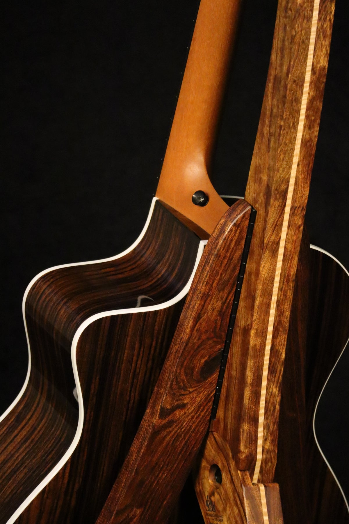 Folding chechen Caribbean rosewood and curly maple wood guitar floor stand closeup rear image with Taylor guitar