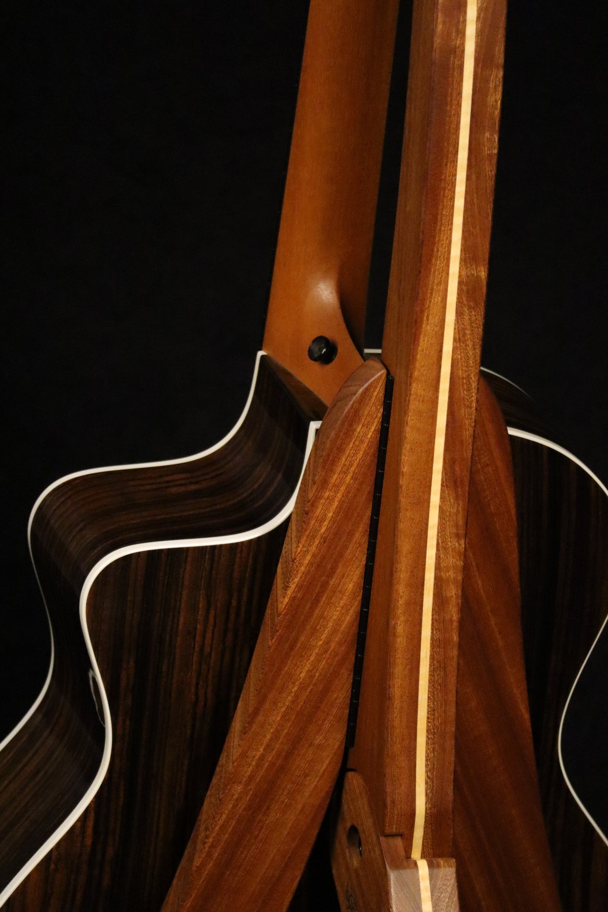 Folding sapele mahogany and curly maple wood guitar floor stand closeup rear image with Taylor guitar