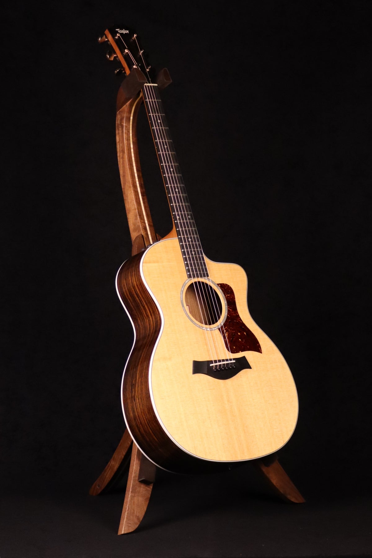 Folding walnut and curly maple wood guitar floor stand full front image with Taylor guitar