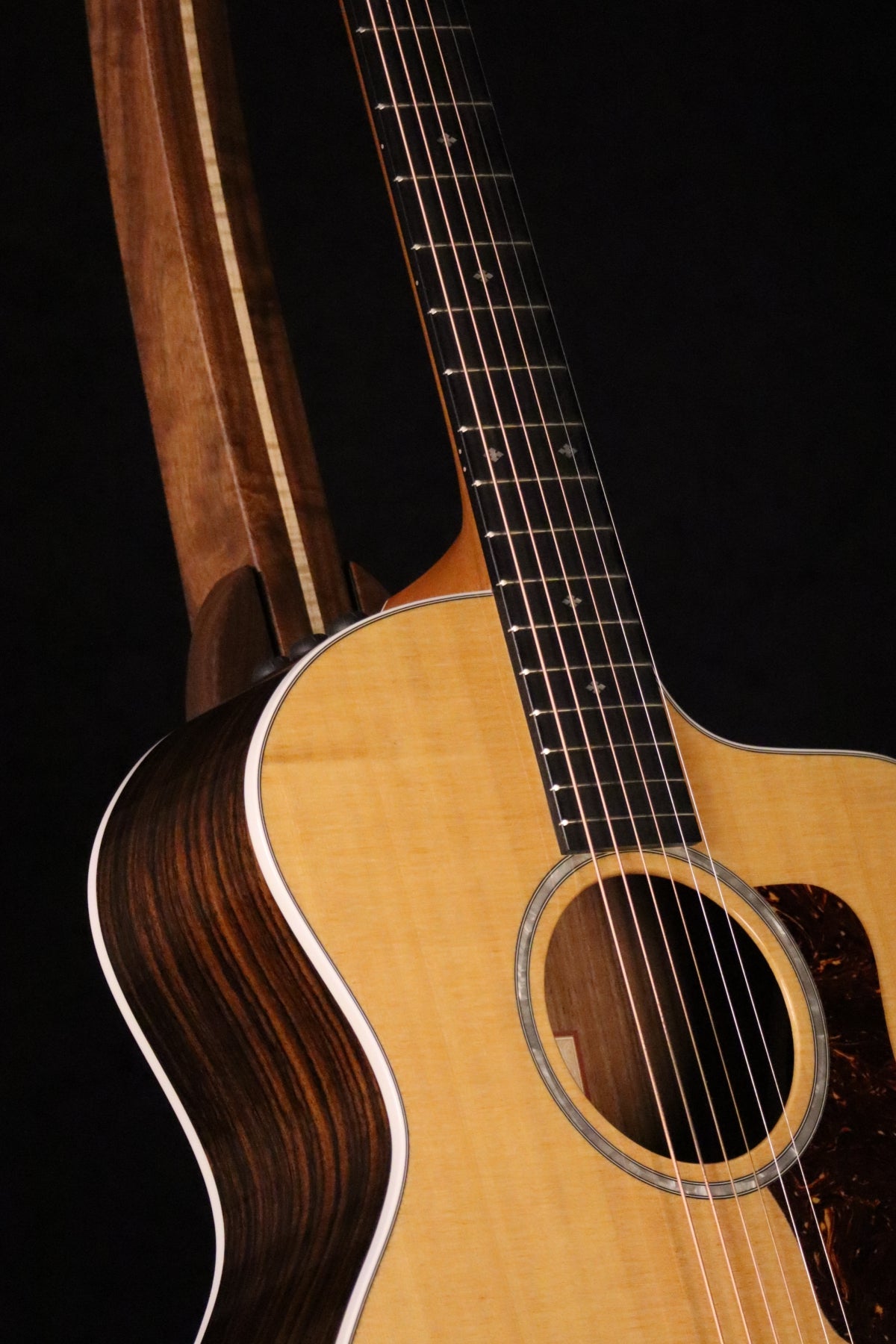 Folding walnut and curly maple wood guitar floor stand closeup front image with Taylor guitar