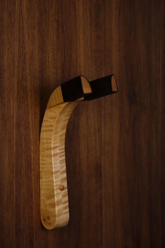 Curly maple wood guitar wall mount hanger installed on paneled wall