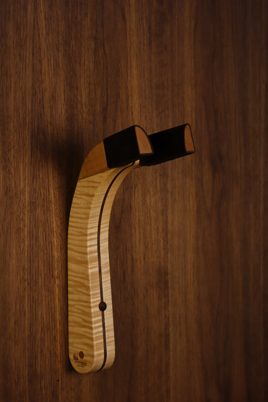 Curly maple and walnut wood guitar wall mount hanger installed on paneled wall