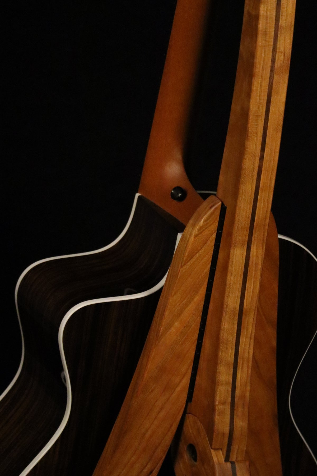 Folding cherry and walnut wood guitar floor stand closeup rear image with Taylor guitar
