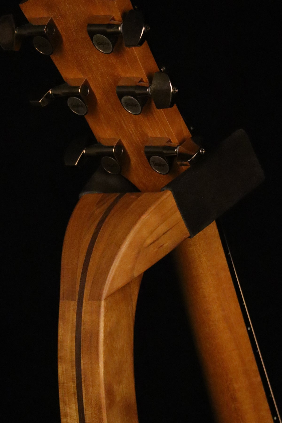 Folding cherry and walnut wood guitar floor stand yoke detail image with Taylor guitar