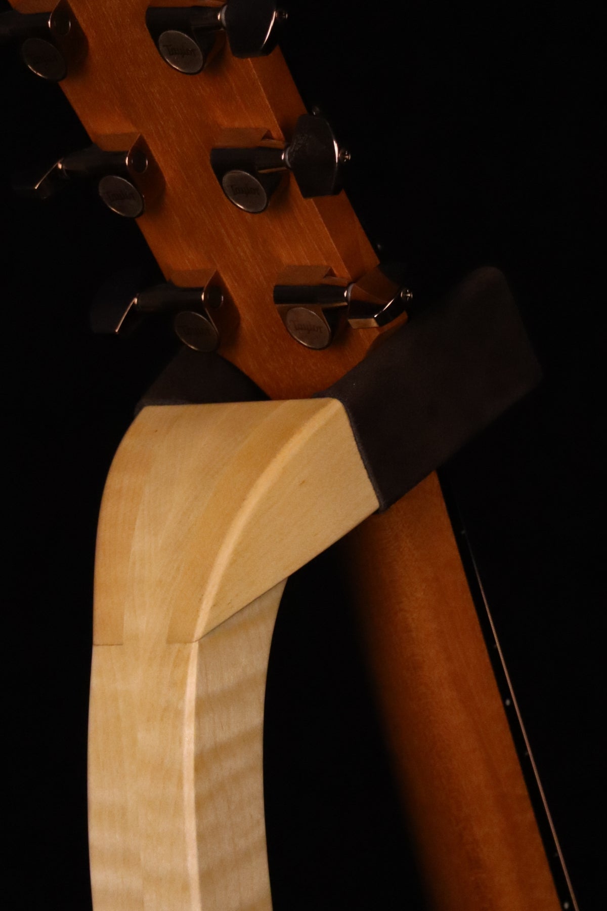 Folding curly maple wood guitar floor stand yoke detail image with Taylor guitar