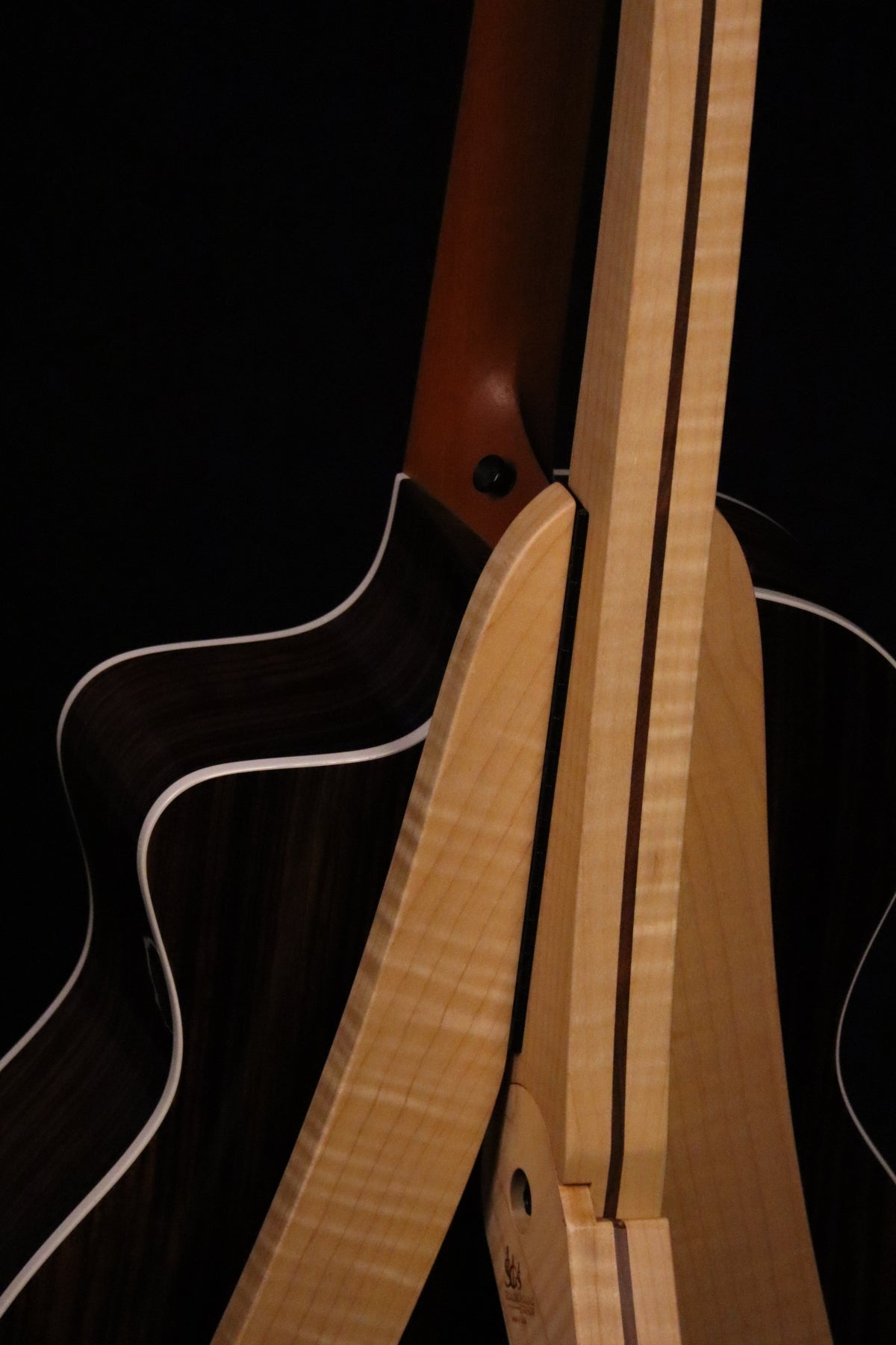 Folding curly maple and walnut wood guitar floor stand closeup rear image with Taylor guitar