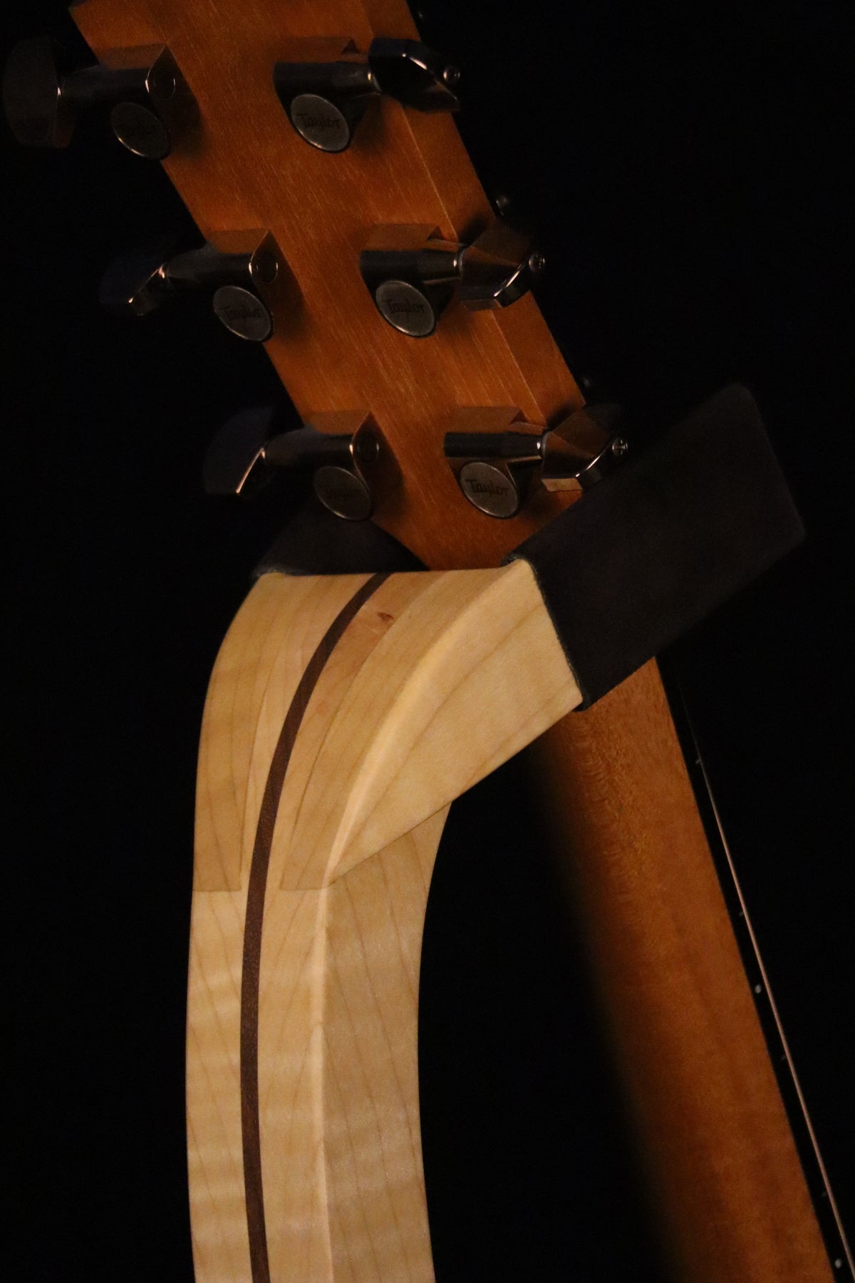 Folding curly maple and walnut wood guitar floor stand yoke detail image with Taylor guitar