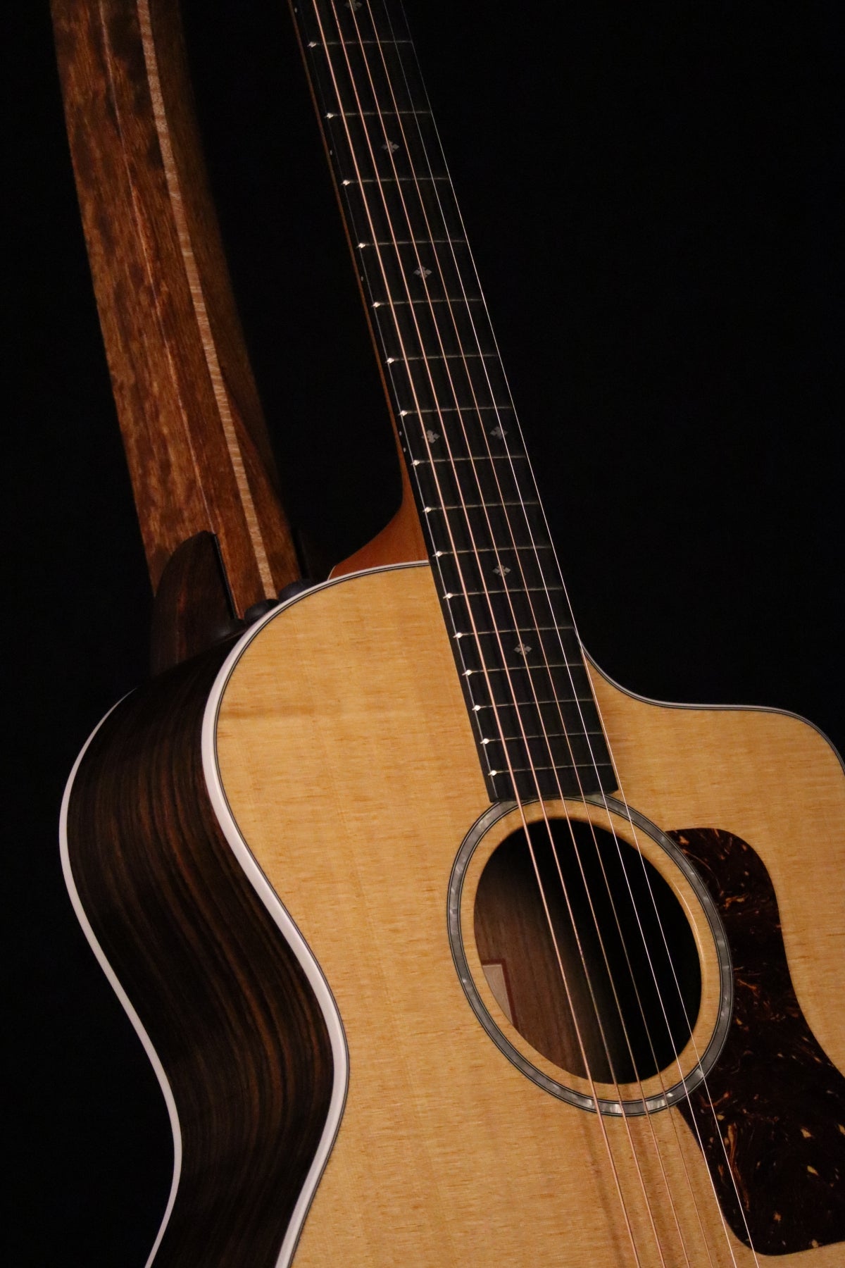 Folding chechen Caribbean rosewood and curly maple wood guitar floor stand closeup front image with Taylor guitar