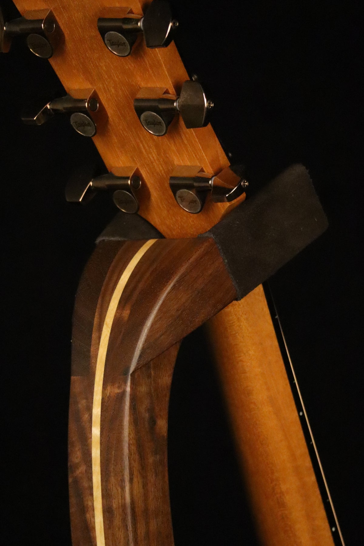 Folding walnut and curly maple wood guitar floor stand yoke detail image with Taylor guitar