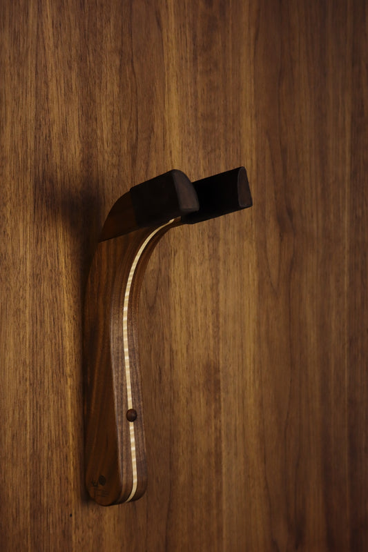 Walnut and curly maple wood guitar wall mount hanger installed on paneled wall